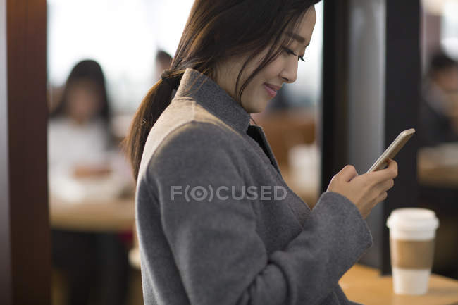 Asiatin benutzt Smartphone am Flughafen — Stockfoto