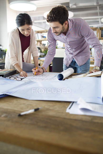 Arquitectos trabajando en planos en la oficina - foto de stock