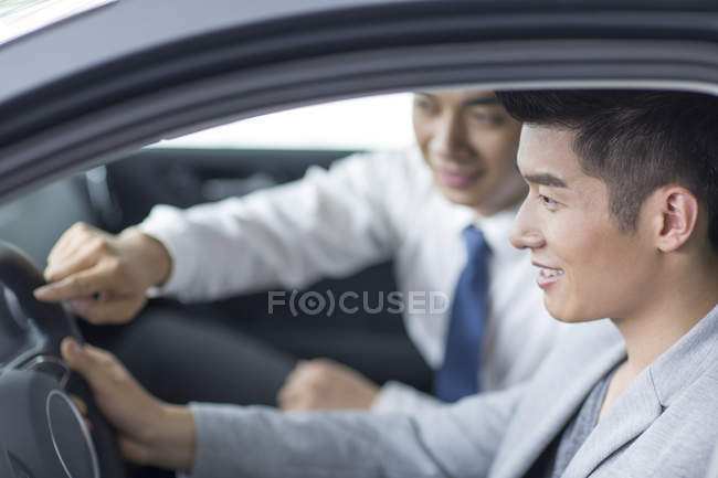 Negociante de carro ajudando o homem com test drive — Fotografia de Stock