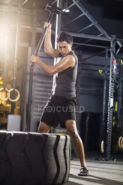 Chinois homme martelant grand pneu à la salle de gym — Photo de stock