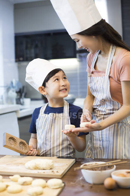 Chinese mother and son in cook hat cooking together — Stock Photo