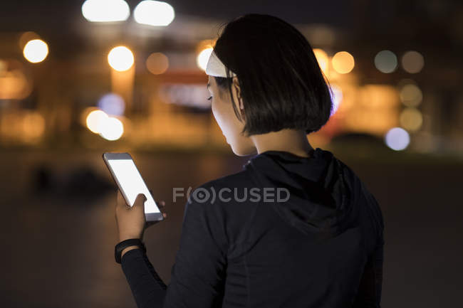 Atleta femenina china escuchando música con smartphone - foto de stock