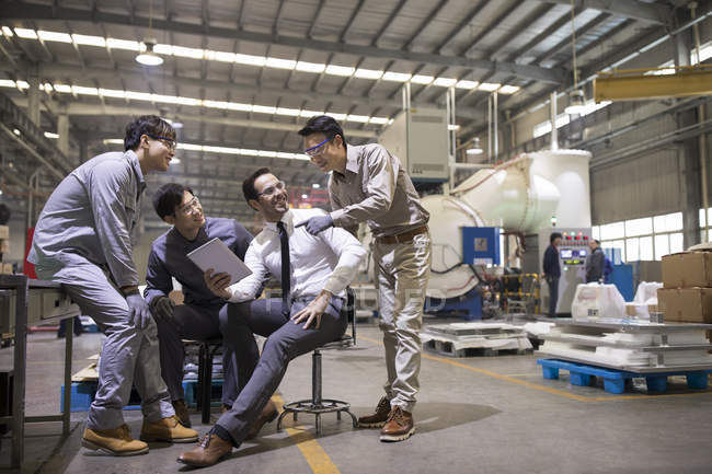 Businessman and Asian engineers using digital tablet and talking at factory — Stock Photo