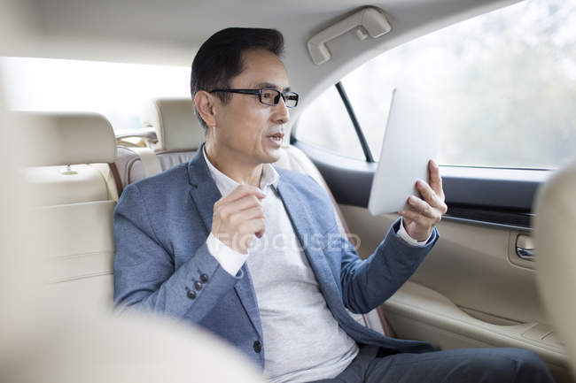 Азіатських людині, використовуючи цифровий планшет на задньому сидінні автомобіля — стокове фото