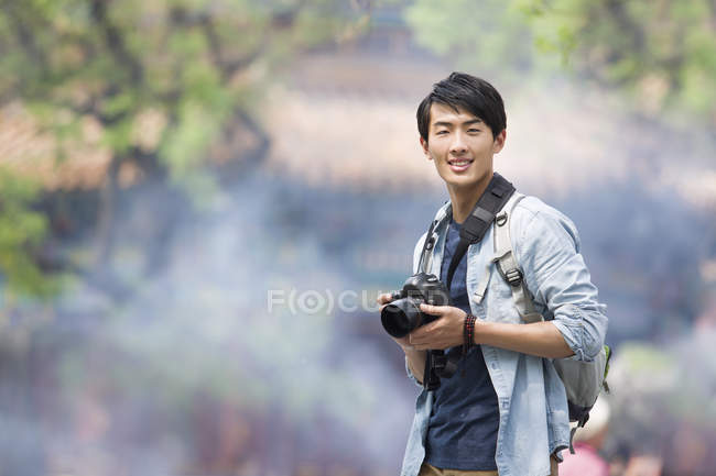 Chinese man standing at Lama Temple with camera — Stock Photo