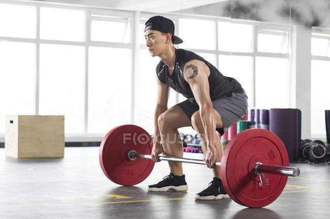 Asian man lifting barbells at gym — Stock Photo