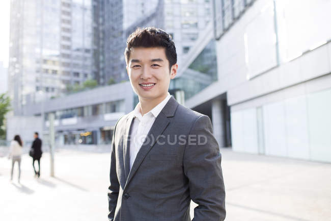 Chinesischer Geschäftsmann steht auf der Straße und schaut in die Kamera — Stockfoto