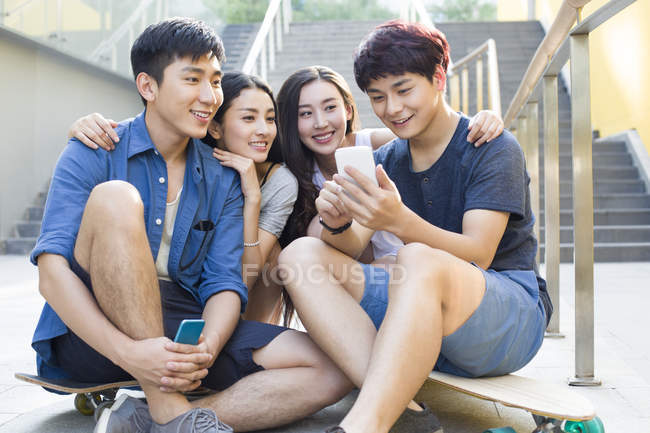 Китайские друзья вместе смотрят на экран смартфона — стоковое фото