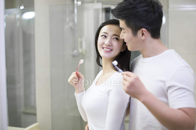Asiática pareja cepillarse los dientes en cuarto de baño - foto de stock
