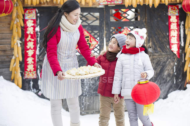 Mother and siblings with traditional Chinese dumplings in village — Stock Photo