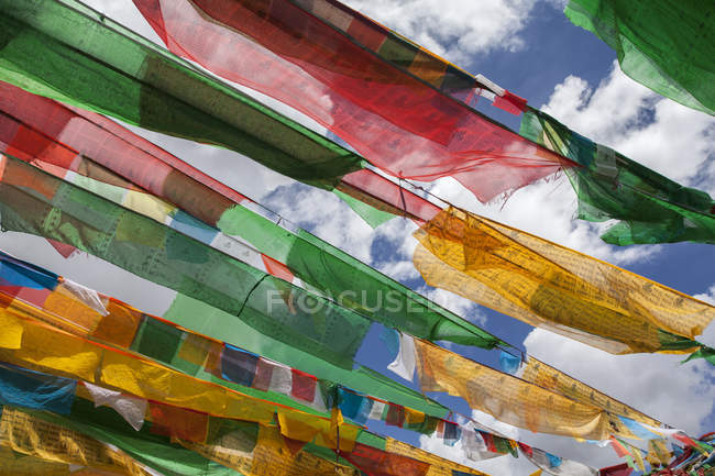 Banderas de oración contra el cielo nublado en el Tíbet, China - foto de stock