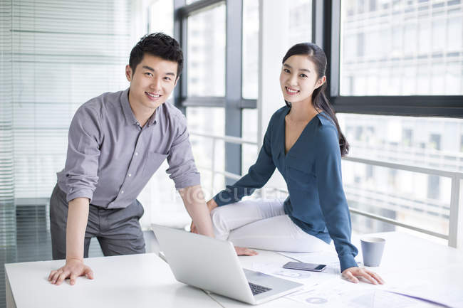 Chinese co-workers sitting with laptop in office — Stock Photo