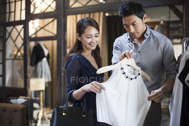Pareja china eligiendo vestido en tienda de ropa - foto de stock