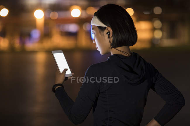 Chinese female athlete listening to music with smartphone — Stock Photo