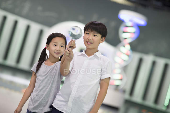 Chinese children holding magnifying glass in museum — Stock Photo