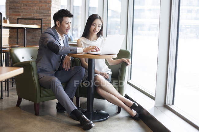 Азиатские мужчина и женщина работают с ноутбуком в кафе — стоковое фото