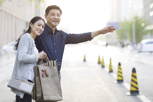Mature chinese couple on taxi stand after shopping — Stock Photo
