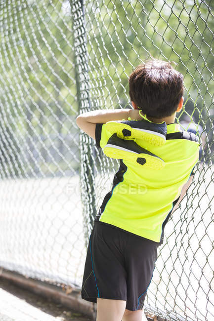 Вид сзади на мальчика в спортивной одежде, смотрящего на детскую площадку — стоковое фото
