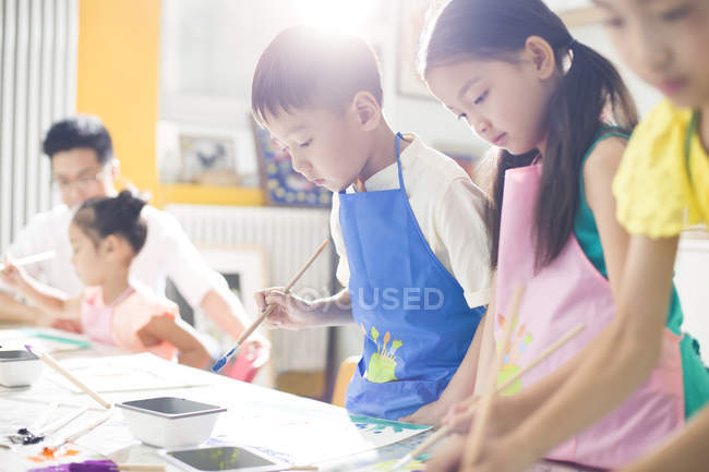 Китайские дети рисуют в художественном классе с учителем — стоковое фото