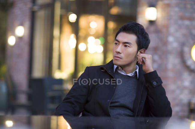 Asiatischer Mann sitzt am Tisch auf städtischer Straße — Stockfoto
