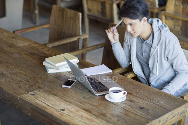 Homem chinês estudando com laptop no café — Fotografia de Stock