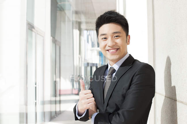 Retrato del hombre de negocios chino haciendo pulgares hacia arriba - foto de stock