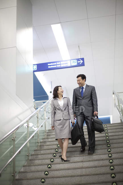 Chinese business people walking down on steps at subway station — Stock Photo