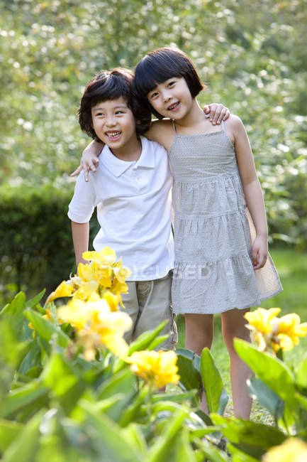 Enfants chinois embrassant dans le jardin avec des fleurs — Photo de stock