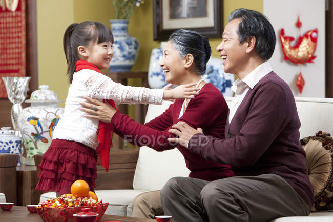Бабушка и дедушка обнимают внучку во время китайского Нового года — стоковое фото