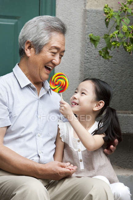 Nonno e nipote cinesi seduti con lecca-lecca sul portico — Foto stock