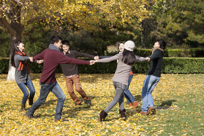 Jovens adultos chineses correndo em círculo no parque no outono — Fotografia de Stock