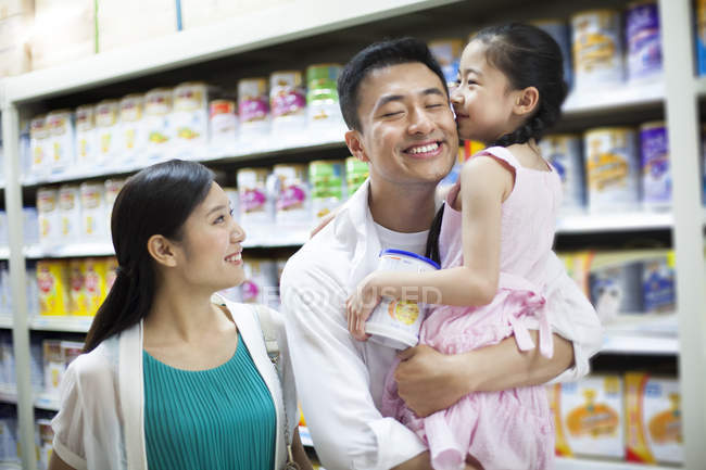 Chinese girl kissing father in supermarket — Stock Photo