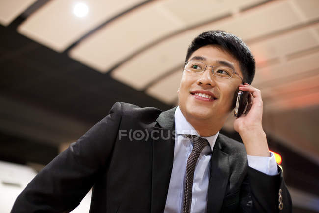 Chinese businessman talking on phone at train station — Stock Photo