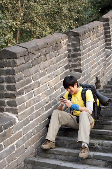 Chinese tourist using smartphone on Great Wall steps — Stock Photo