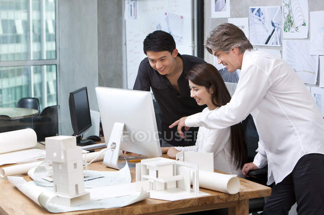 Зрелые люди и китайские архитекторы, работающие с компьютером в офисе — стоковое фото