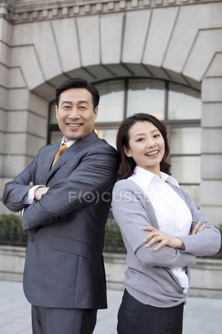 Confident Chinese business people standing back to back in financial district — Stock Photo