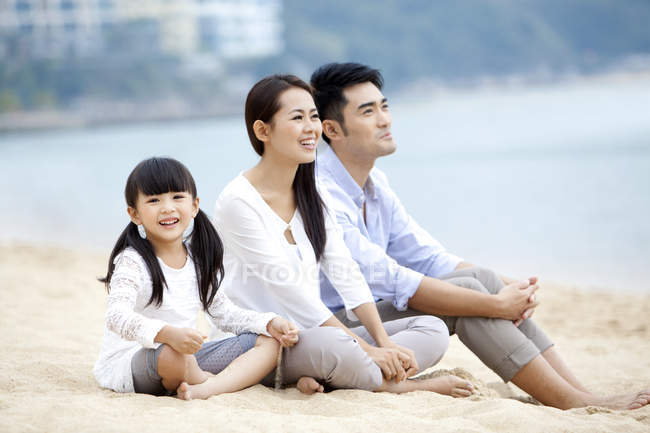 Famiglia cinese con figlia appoggiata sulla sabbia della spiaggia — Foto stock