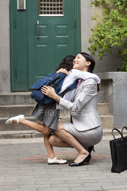Femme chinoise et écolière étreignant dans la rue — Photo de stock