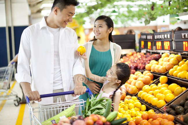 Menina chinesa com pais comprando frutas no supermercado — Fotografia de Stock