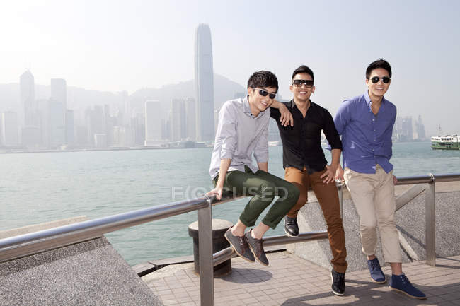 Young Chinese men sitting on balustrade in Victoria Harbor, Hong Kong — Stock Photo