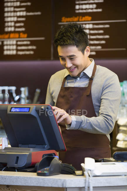 Male Chinese coffee store clerk working at cash register — Stock Photo