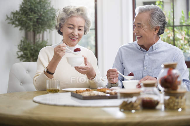 Senior pareja china desayunando con dulces - foto de stock