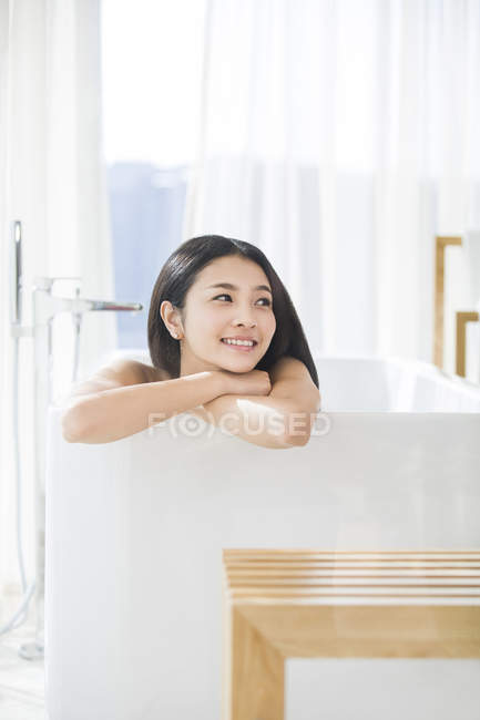 Mulher chinesa deitada na banheira e olhando para longe — Fotografia de Stock