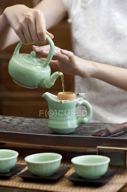 Mulher em cheongsam tradicional segurando bule e chá derramando — Fotografia de Stock