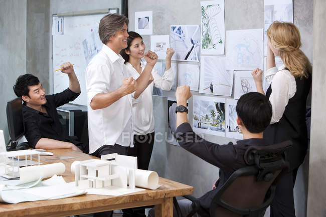 Team di architetti che guardano al muro e applaudono in ufficio — Foto stock