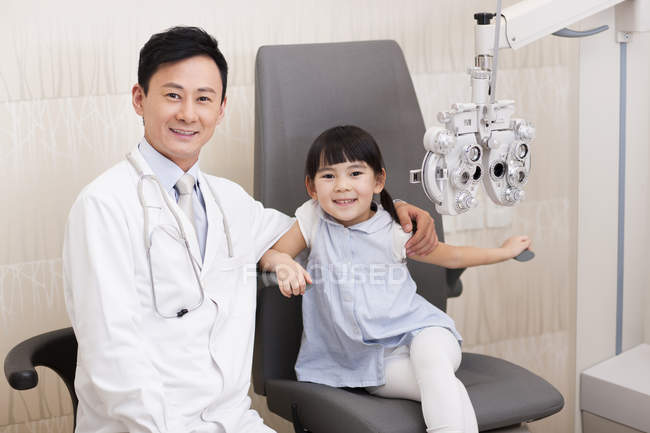 Optometrista chino sentado con chica en silla - foto de stock