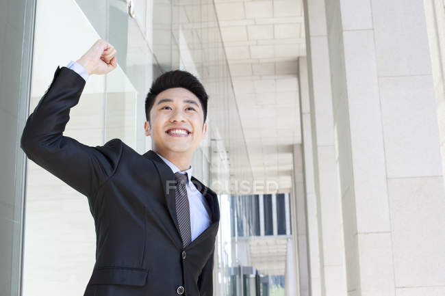 Empresario chino animando con los brazos levantados - foto de stock