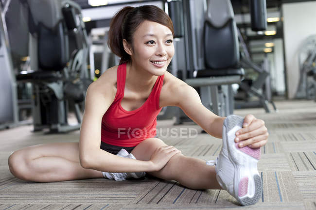 Chinese woman stretching at gym — Stock Photo
