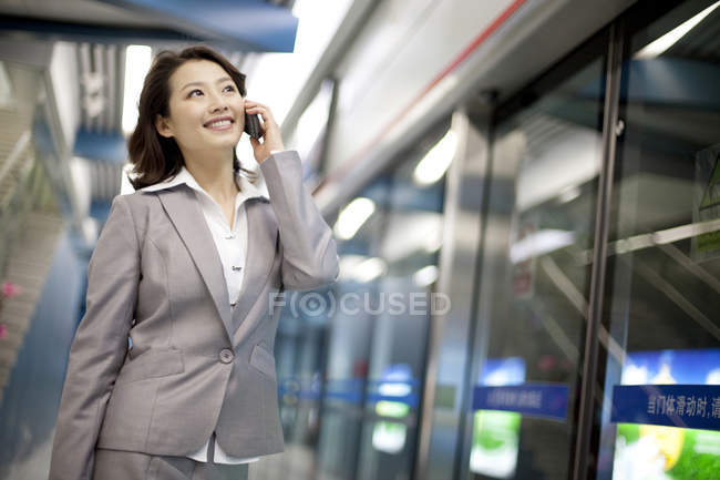 Donna d'affari cinese che parla al telefono alla stazione della metropolitana — Foto stock