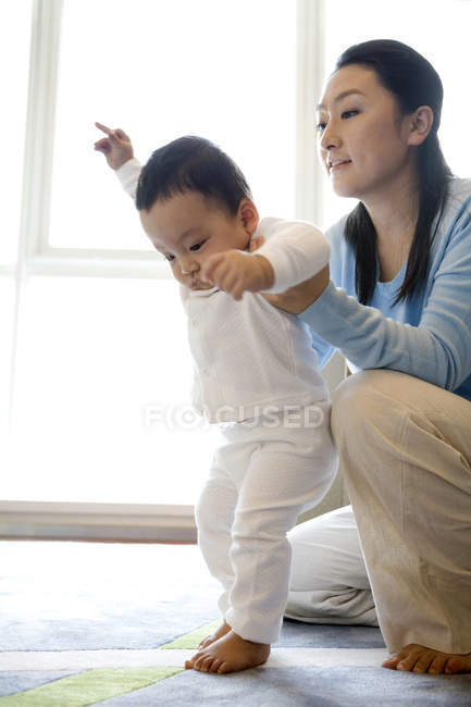 Chinês mulher ajudando filho andando na sala de estar — Fotografia de Stock
